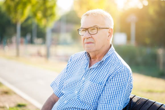 Senior man with glasses sitting outdoors