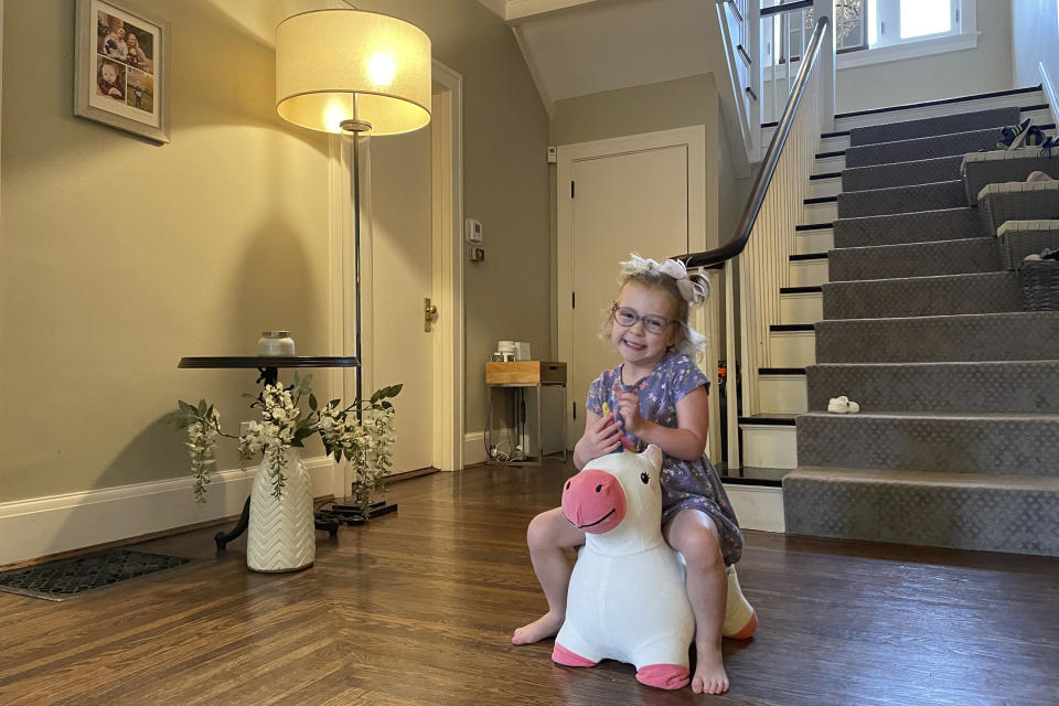 Brynn Schulte rides on a toy unicorn at her home in Cincinnati shortly before getting medication to treat her rare genetic bleeding disorder, Aug. 3, 2023. Brynn was diagnosed thanks to whole genome testing, which was recently shown to be nearly twice as good at finding genetic disorders in sick babies as more targeted tests. Her parents and doctors credit early diagnosis with saving her life. (AP Photo/Laura Ungar)