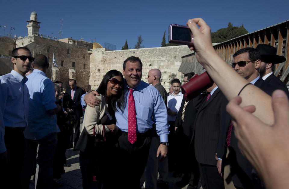 A tourist has her picture taken with New Jersey Gov. Chris Christie, center, during his visit to the Western Wall, the holiest site where Jews can pray, in Jerusalem's old city Monday, April 2, 2012. Christie kicked off his first official overseas trip Monday meeting Israel's leader in a visit that may boost the rising Republican star's foreign policy credentials ahead of November's presidential election. (AP Photo/Sebastian Scheiner)