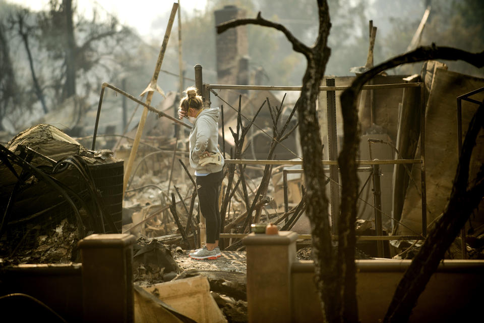 <p>Bree Laubacher pauses while sifting through rubble at her Ventura, Calif., home following a wildfire on Wednesday, Dec. 6, 2017. A barbecue smoker and her son’s batting cage survived the blaze. (Photo: Noah Berger/AP) </p>