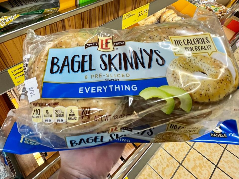 Hand holding blue and clear package of Aldi bagel things