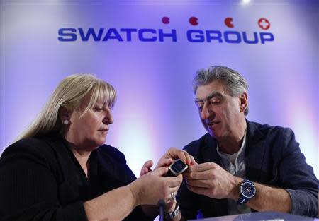 Nick Hayek Jr (R) Swatch Group Chief Executive shows a new Swatch model to his sister Nayla Hayek, Group Chair of the Board, before the Swiss watch maker annual news conference in Plan-Les-Ouates near Geneva March 20, 2014. REUTERS/Denis Balibouse