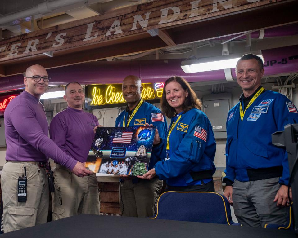 NASA astronauts Victor Glover, Shannon Walker, and Andrew Morgan present a gift to the crew of the aircraft carrier USS Nimitz. The astronauts presented an American flag, which was flown in space, to the crew of the Nimitz as a gesture of appreciation during their visit.