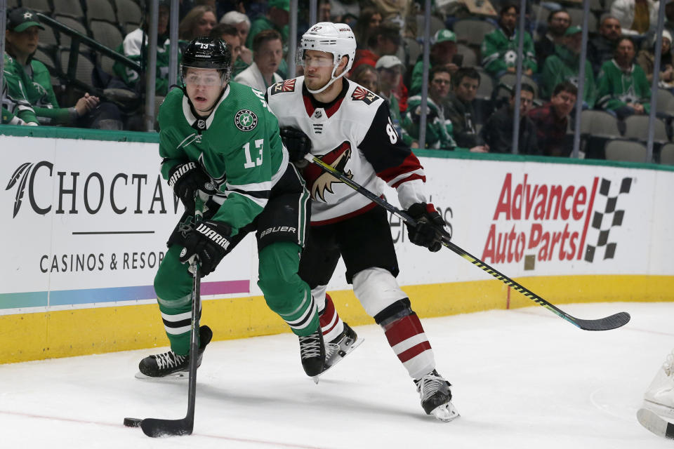 Dallas Stars center Mattias Janmark (13) works with the puck next to Arizona Coyotes defenseman Jordan Oesterle (82) during the first period of an NHL hockey game in Dallas, Wednesday, Feb. 19, 2019. (AP Photo/Michael Ainsworth)