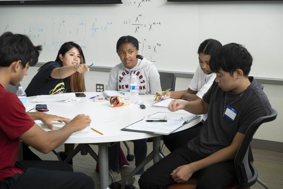 Rosa Sarmiento, second from left, and Alicia Davis, center, work together to solve the math equation written on a whiteboard during a summer math boot camp session on Thursday, Aug. 1, 2023 at George Mason University in Fairfax. Va. (AP Photo/Kevin Wolf)