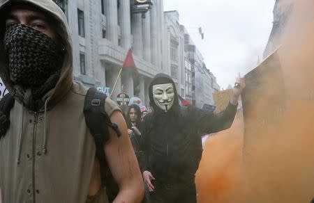 Demonstrators cover their faces as they march through coloured smoke during an anti-austerity protest in central London, Britain June 20, 2015. REUTERS/Suzanne Plunkett