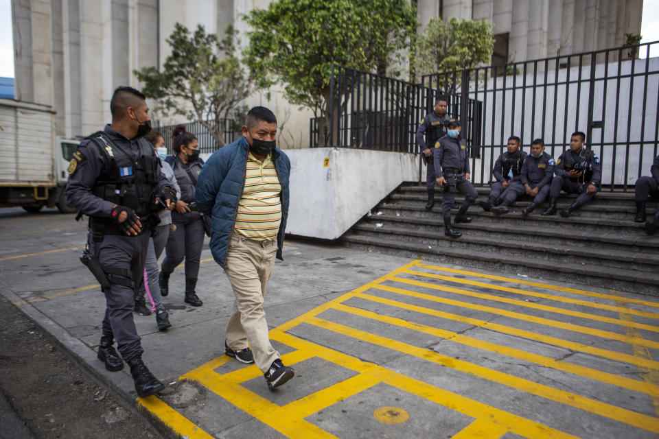 FILE - David Coronado Perez, who is allegedly part of a human trafficking network, is escorted by an officer at the end of his court hearing, in Guatemala City, Friday, Feb. 4, 2022. Coronado’s lawyer said his client is innocent and that Coronado is a farmer, not a smuggler, and is himself a victim because his son was among those killed in Mexico. (AP Photo/Oliver de Ros, File)