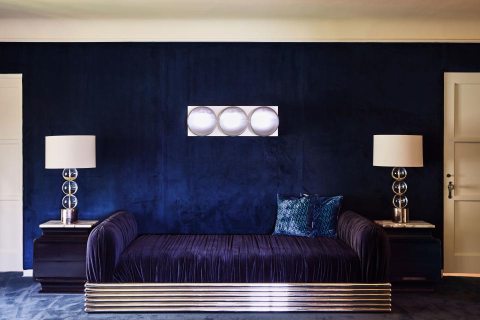 The master bedroom is like a sapphire blue jewel box. Suede walls match the plush carpeting and rich upholstery and linens. “I saw a picture of, maybe, Valentino’s study in the '70s,” says Ronson. “He had this matching carpet and walls, but it was this teal green thing. For me, it was just easier to go with blue.” This is the view from the foot of his bed. Above the couch is a light fixture Ronson acquired one year at Design Miami/Basel. Each bulb has its own transporting projection within: mellow scenes of hypnotic rain or the calm seas. “It’s just nice to sit on the bed and stare at,” says Ronson whose whirlwind in-demand schedule has him crisscrossing the globe, playing lots of late-night gigs.
