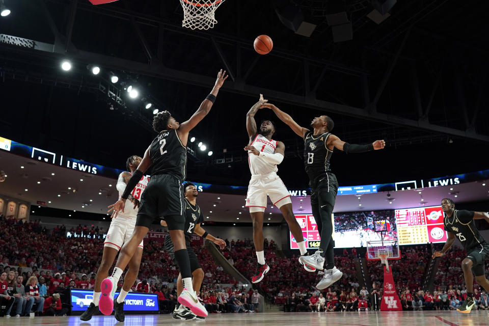 Houston's Jamal Shead (1) goes up for a shot as Central Florida's Michael Durr (2) and C.J. Kelly (13) defend during the first half of an NCAA college basketball game Saturday, Dec. 31, 2022, in Houston. (AP Photo/David J. Phillip)