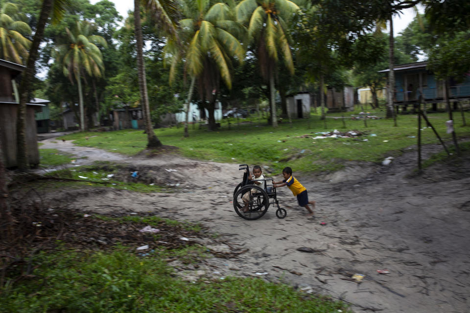 En esta fotografía del 6 de febrero de 2018, Charles Meléndez, de 5 años, y su hermano de 4, Jefferson, juegan con la silla de ruedas de su padre en Puerto Lempira, Honduras. El padre de los pequeños, un buzo de pesca de langostas, se recupera de un síndrome de descompresión que lo ha dejado paralizado de la cintura para abajo. (AP Foto/Rodrigo Abd)