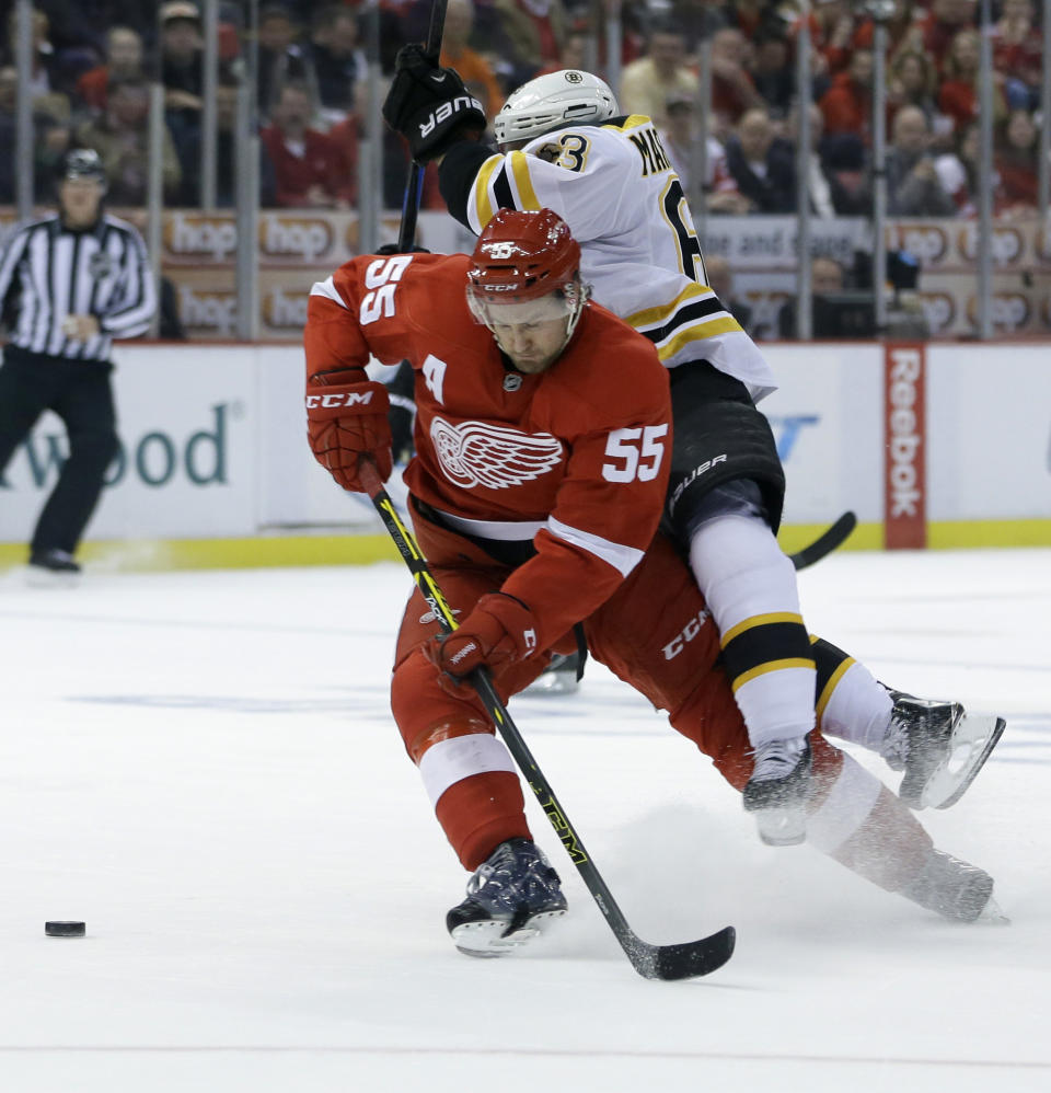 Boston Bruins left wing Brad Marchand (63) falls over Detroit Red Wings defenseman Niklas Kronwall (55) of Sweden as they chase the puck during the first period of Game 3 of a first-round NHL hockey playoff series in Detroit, Tuesday, April 22, 2014. (AP Photo/Carlos Osorio)