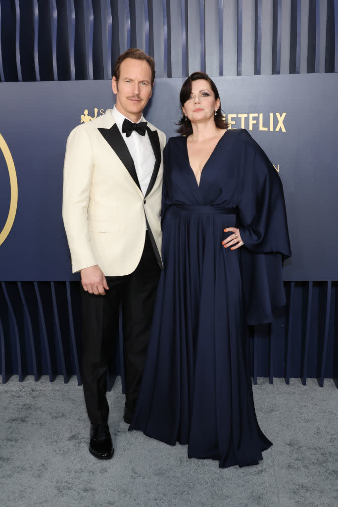 Patrick Wilson and Dagmara Dominczyk posing at an event, he's in a white jacket and black bow tie, and she's in a flowing long gown