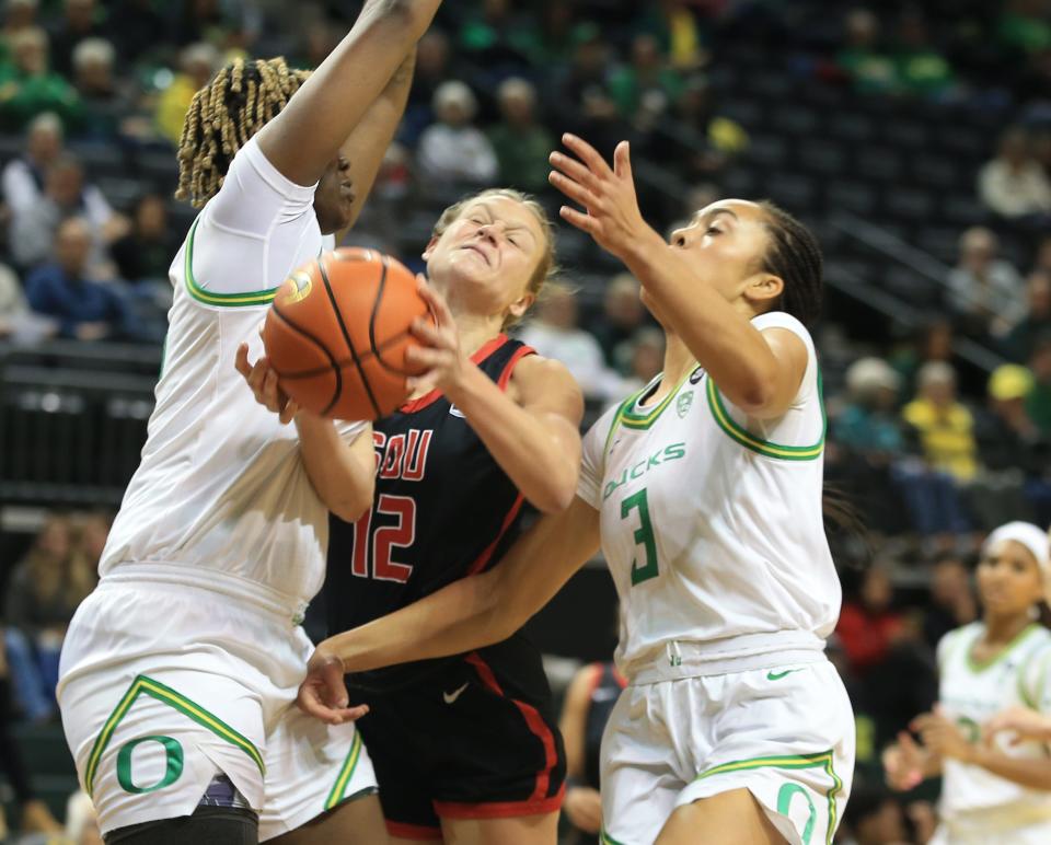 Southern Oregon’s Keeley Wright, center, runs into traffic supplied by Oregon’s Phillipina Kyei, left, and Sofia Bell during the first half at Matthew Knight Arena Oct. 29, 2023 in Eugene, Oregon.