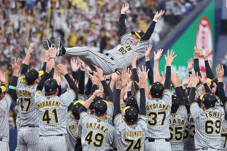 Hanshin Tigers players hoist manager Akinobu Okada into the air to celebrate winning the Nippon Professional Baseball championship. (Jiji Press/AFP via Getty Images)