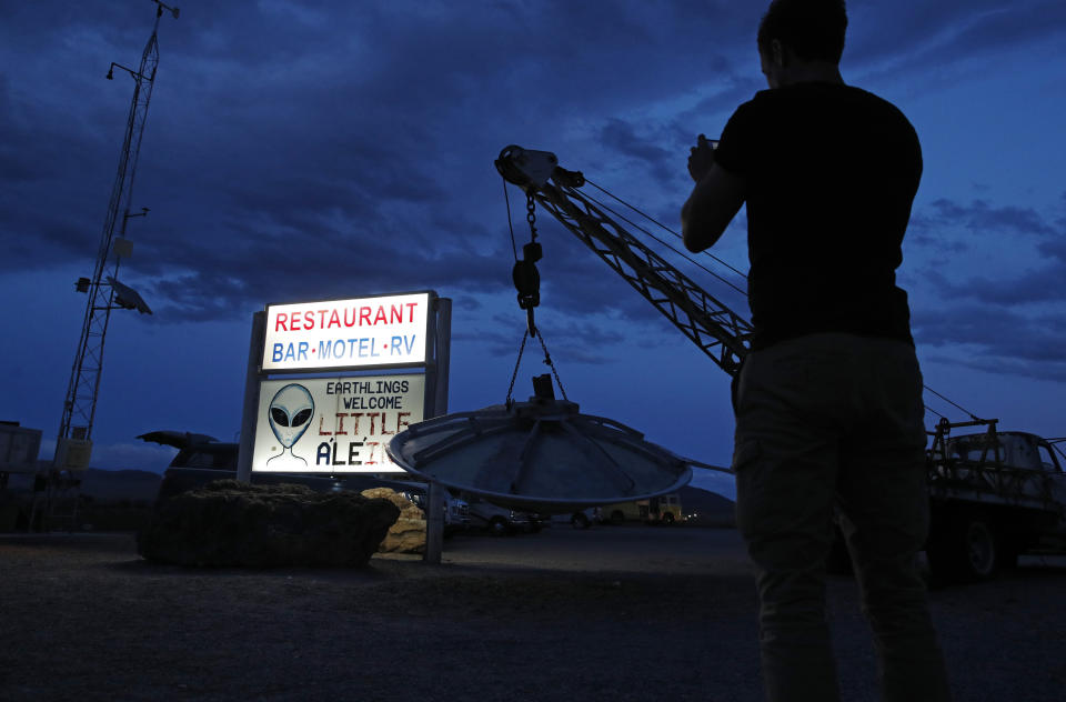 A man takes a picture of a sign at the Little A'Le'Inn during an event inspired by the "Storm Area 51" internet hoax, Thursday, Sept. 19, 2019, in Rachel, Nev. Hundreds have arrived in the desert after a Facebook post inviting people to "see them aliens" got widespread attention and gave rise to festivals this week. (AP Photo/John Locher)