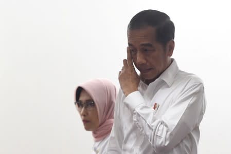 Indonesian President Joko Widodo gestures as he arrives with Sripeni Inten Cahyani, who is PLN's acting CEO, during a visit at PT Perusahaan Listrik Negara (PLN) headquarters after a major power blackout in Jakarta