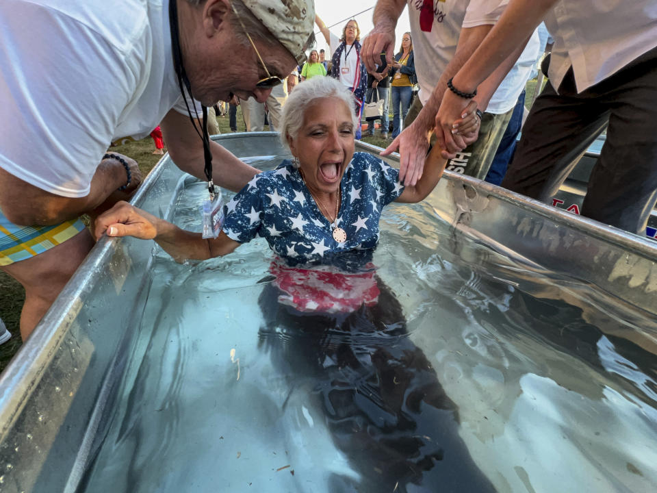 A woman is baptized during the ReAwaken America Tour at Cornerstone Church in Batavia, N.Y., Friday, Aug. 12, 2022. In the version of America laid out at the ReAwaken tour, Christianity is at the center of American life and institutions, it's under attack, and attendees need to fight to restore and protect the nation's Christian roots. It’s a message repeated over and over at ReAwaken — one that upends the constitutional ideal of a pluralist democracy. (AP Photo/Carolyn Kaster)