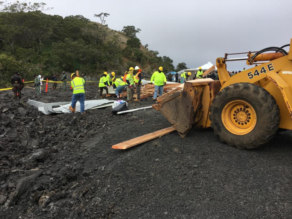 Crews and police gather at a lava field on Hawaii's Mauna Kea on the big island on Friday, Sept. 6, 2019 while a small wooden house is demolished. Opponents of a giant telescope built the unpermitted structure near their protest camp. (Dan Dennison/Department of Land and Natural Resources via AP)