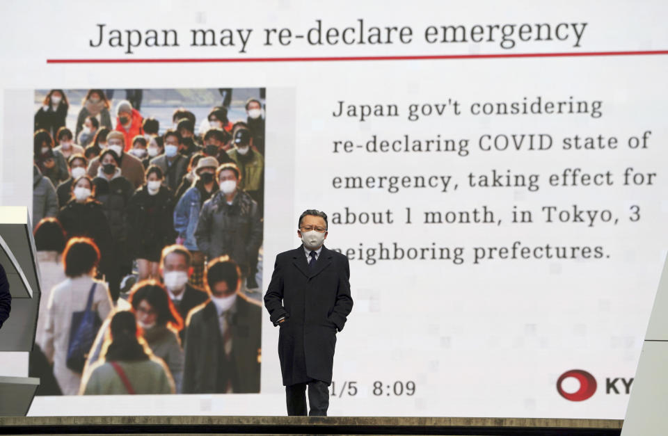 FILE - In this Jan. 5, 2021, file photo, a man wearing a mask against the spread of the coronavirus walks in front of a screen showing the news on possible Japan's State of Emergency in Tokyo. Opposition to the Tokyo Olympics is growing with calls for a cancellation as virus cases rise in Japan. The International Olympic Committee and local organizers have already said another postponement is impossible, leaving cancellation, or going ahead, as the only options. (AP Photo/Eugene Hoshiko, File)