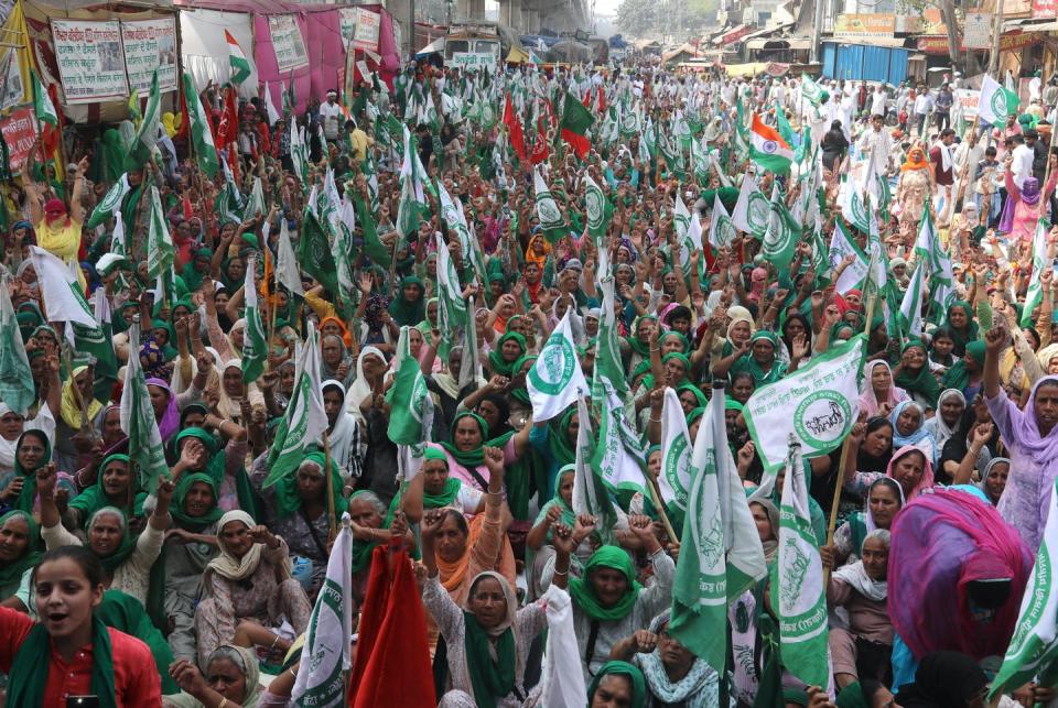 Crowd of hundreds of women holding green flags and raising their fists in the streets