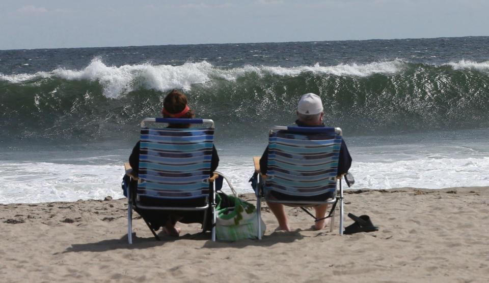 A couple watches the waves at Hampton Beach on Friday, Sept. 15, 2023 ahead of the expected impact of high winds and waves Saturday as a result of Hurricane Lee passing out to sea.