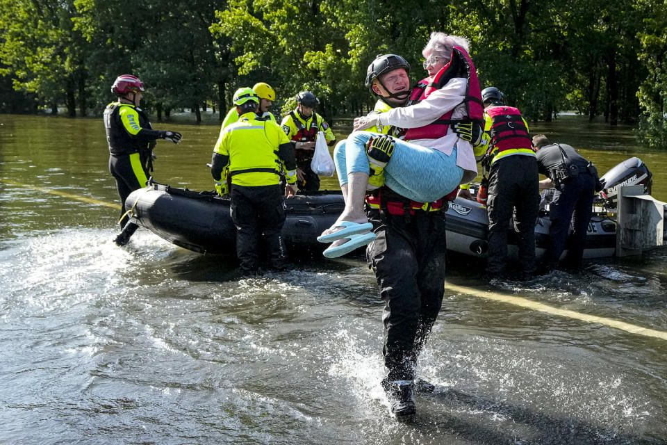 A firefighter carries a resident evacuated in a boat. (Brett Coomer / Houston Chronicle via Getty Images)