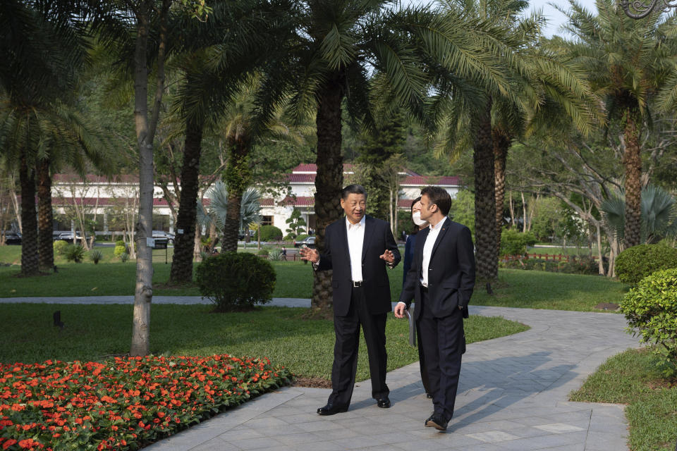 Chinese President Xi Jinping, left, and French President Emmanuel Macron walk in the garden of the Guandong province governor's residence, in Guangzhou, China, Friday, April 7, 2023. (Jacques Witt, Pool via AP)