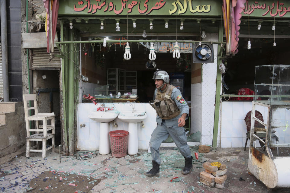 An Afghan police officer searches the area after a multi-pronged attack on a police station in Jalalabad, the capital of eastern Nangarhar province, Afghanistan, Thursday, March 20, 2014. Taliban insurgents staged the attack, using a suicide bomber and gunmen to lay siege to the station, government officials said. Two remotely detonated bombs also exploded nearby. (AP Photo/Rahmat Gul)