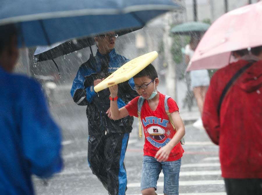 雷雨彈轟炸！北北基升級豪雨 北部5縣市豪大雨特報。圖為小朋友拿起浮板遮雨快跑過馬路。（資料照 陳信翰攝）
