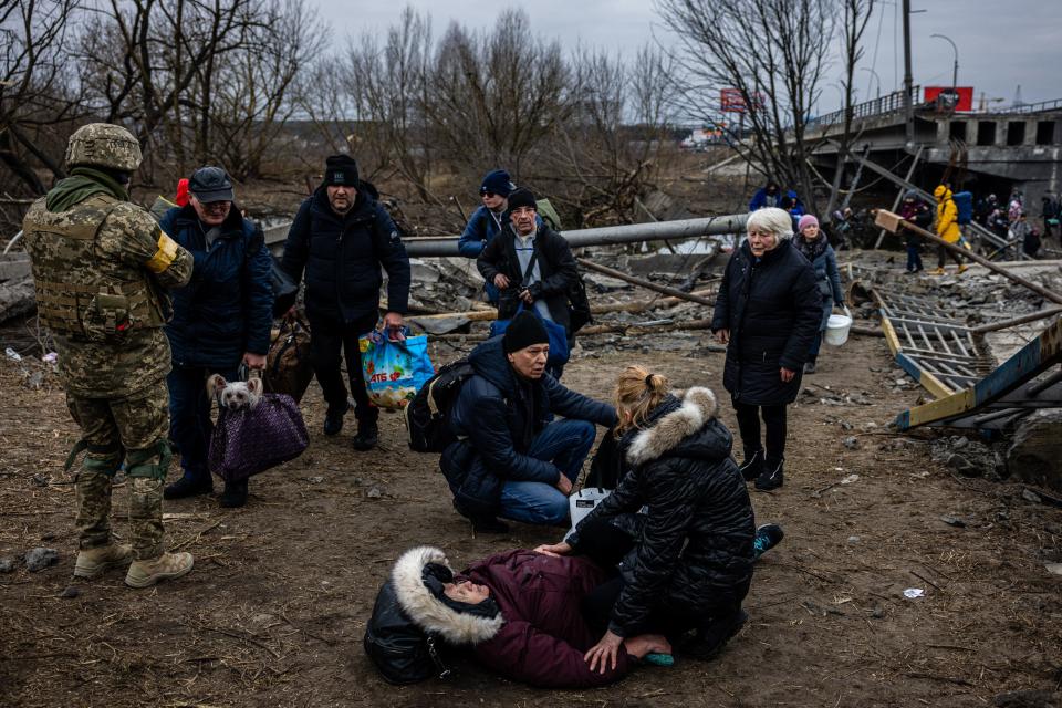 Evacuees cross a destroyed bridge as they flee the city of Irpin, northwest of Kyiv, on March 7, 2022. - Ukraine dismissed Moscow's offer to set up humanitarian corridors from several bombarded cities on Monday after it emerged some routes would lead refugees into Russia or Belarus. The Russian proposal of safe passage from Kharkiv, Kyiv, Mariupol and Sumy had come after terrified Ukrainian civilians came under fire in previous ceasefire attempts. (Photo by Dimitar DILKOFF / AFP) (Photo by DIMITAR DILKOFF/AFP via Getty Images)