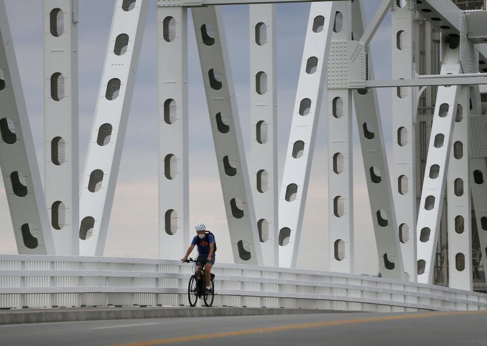 A cyclist rides over a bridge with metal girders.