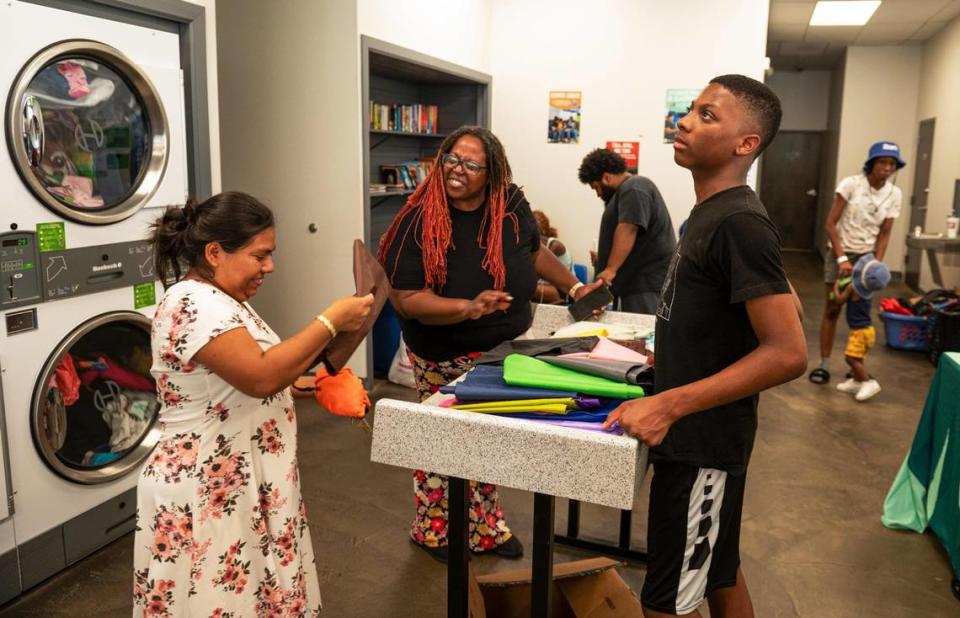 Catalina Luis, left, receives a free laundry bag from Kim Weaver while Elijah Ricketts stands by at Leah’s Laundromat on the Q.