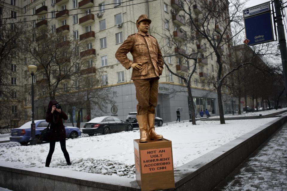 FILE - In this photo taken on Friday Feb. 7, 2014 a member of pro-Kremlin Young Guards of United Russia photographs a monument to a Nazi soldier outside a building, where the CNN Moscow office is located, as a protest against the CNN poll on the most ugly monuments in the world, which included the WWII monument in Brest, Belarus. U.S. television network CNN caused a firestorm when it included a war monument in Brest, a city in the former Soviet republic of Belarus, in an article on the “world’s ugliest monuments” published Jan. 24. (AP Photo/Alexander Zemlianichenko, file)