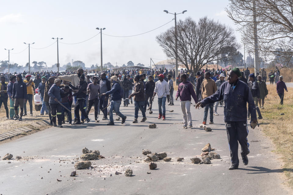 People demonstrate in the South African city of Krugersdorp Thursday Aug. 4, 2022. Community members in the assaulted suspected illegal miners and set fire to their camps on Thursday in an outpouring of anger following the alleged gang rapes of eight women by miners last week. Residents of Krugersdorp's Kagiso township also barricaded roads with rocks and burning tires during a planned protest. (AP Photo/ Shiraaz Mohamed)