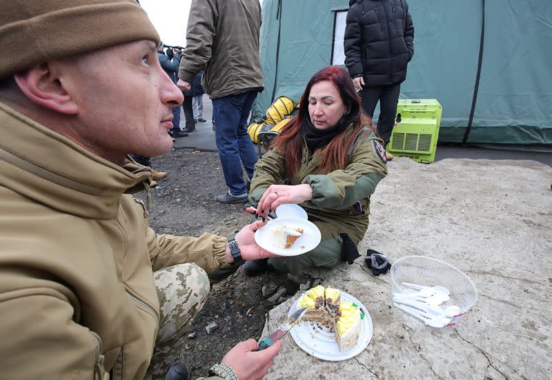 Participants of a welcoming ceremony slice a cake for Ukrainian citizens following prisoner of war exchange in Donetsk region