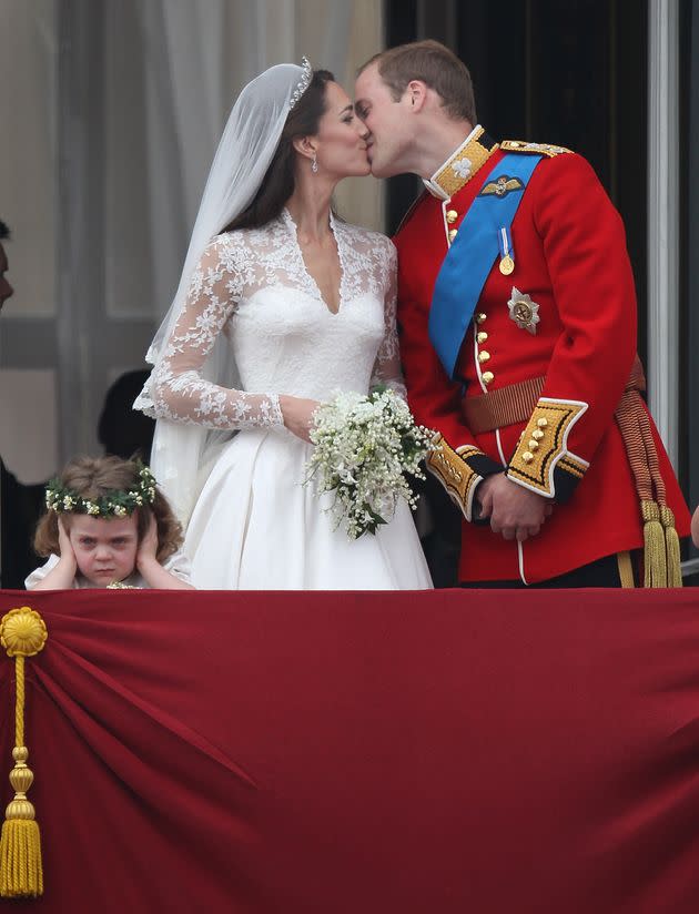 The Duke and Duchess of Cambridge kiss as bridesmaid Grace Van Cutsem looks at the crowd from the balcony at Buckingham Palace on April 29, 2011, in London. (Photo: Peter Macdiarmid via Getty Images)