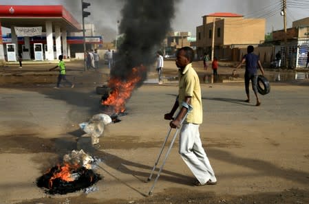 A disabled man walks past a barricade erected by Sudanese protesters along a street, demanding that the country's Transitional Military Council hand over power to civilians, in Khartoum