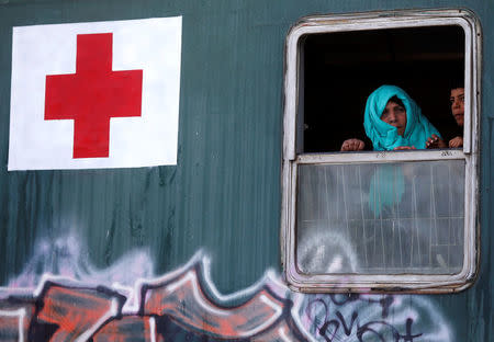 A woman and a boy look out of a window of a train, used as temporary housing, at a makeshift camp for migrants and refugees at the Greek-Macedonian border near the village of Idomeni, Greece, April 22, 2016. REUTERS/Stoyan Nenov