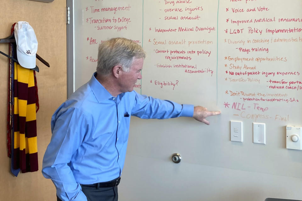 NCAA President Mark Emmert points to a dry erase board in office Wednesday, July 21, 2021, at NCAA headquarters in Indianapolis. Emmert is now the second-longest tenured leader in the long history of the NCAA. Over 11 years, he has guided the NCAA through a period of unprecedented change amid relentless criticism. (AP Photo/Ralph Russo)