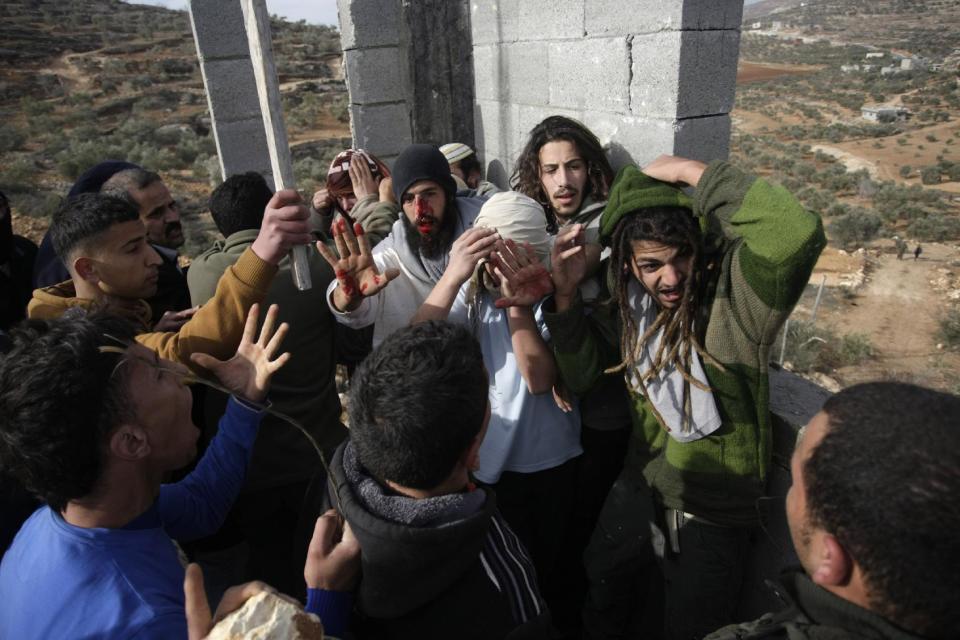 Palestinians hit Israeli settlers who are later detained by Palestinian villagers in a building under construction near the West Bank village of Qusra, southeast of the city of Nablus, Tuesday, Jan. 7, 2014. Palestinians held more than a dozen Israeli settlers for about two hours Tuesday in retaliation for the latest in a string of settler attacks on villages in the area, witnesses said. The military said the chain of events apparently began after Israeli authorities removed an illegally built structure in Esh Kodesh, a rogue Israeli settlement in the area. In recent years, militant settlers have often responded to any attempts by the Israeli military to remove parts of dozens of rogue settlements, or outposts, by attacking Palestinians and their property. The tactic, begun in 2008, is known as "price tag." (AP Photo/Nasser Ishtayeh)