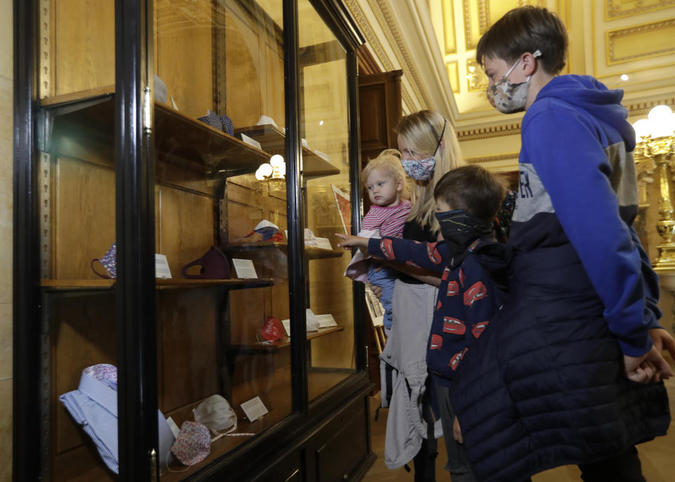 Visitors view en exhibition of face masks at the National Museum in Prague, Czech Republic, Thursday, May 28, 2020. With the coronavirus pandemic still not over yet, the Czech National Museum in Prague has put on display the most visible symbol of the country's response to it, face masks.(AP Photo/Petr David Josek)