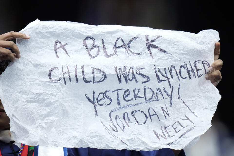A graduate holds a sign reading "A Black child was lynched yesterday! Jordan Neely" as President Joe Biden speaks at Howard University's commencement in Washington, Saturday, May 13, 2023. (AP Photo/Alex Brandon)