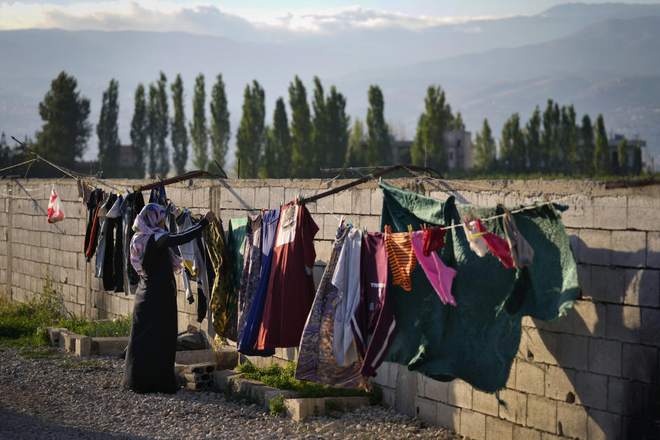 A Syrian refugee hangs her family's laundry outside her tent at a refugee camp in the town of Bar Elias, in the Bekaa Valley, Lebanon, July 7, 2022. The Lebanese government’s plan to start deporting Syrian refugees has sent waves of fear through vulnerable refugee communities already struggling to survive in their host country. Many refugees say being forced to return to the war shattered country would be a death sentence. (AP Photo/Bilal Hussein)