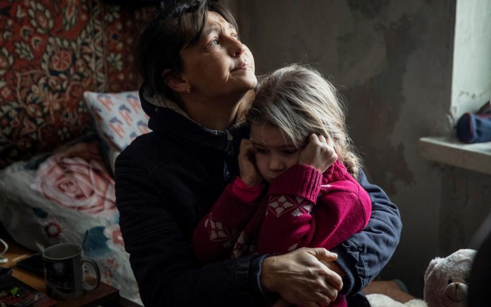 A grandmother Olha hugs her granddaughter Arina, 6, while saying goodbye before her evacuation from front line city of Bakhmut - STRINGER/REUTERS