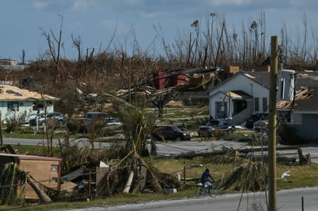 A man rides a bicycle past damage in the wake of Hurricane Dorian in Marsh Harbour