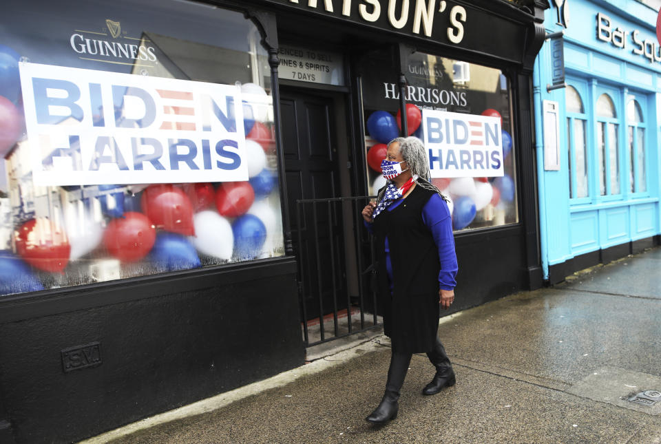 A woman wearing a face mask walks past a pub supporting Joe Biden and Kamala Harris in Ballina, Ireland, Wednesday, Jan. 20, 2021. Joe Biden's great-great grandfather Patrick Blewitt was born in Ballina, County Mayo, in 1832. He left for the US in 1850, aged 18. (AP Photo/Peter Morrison)