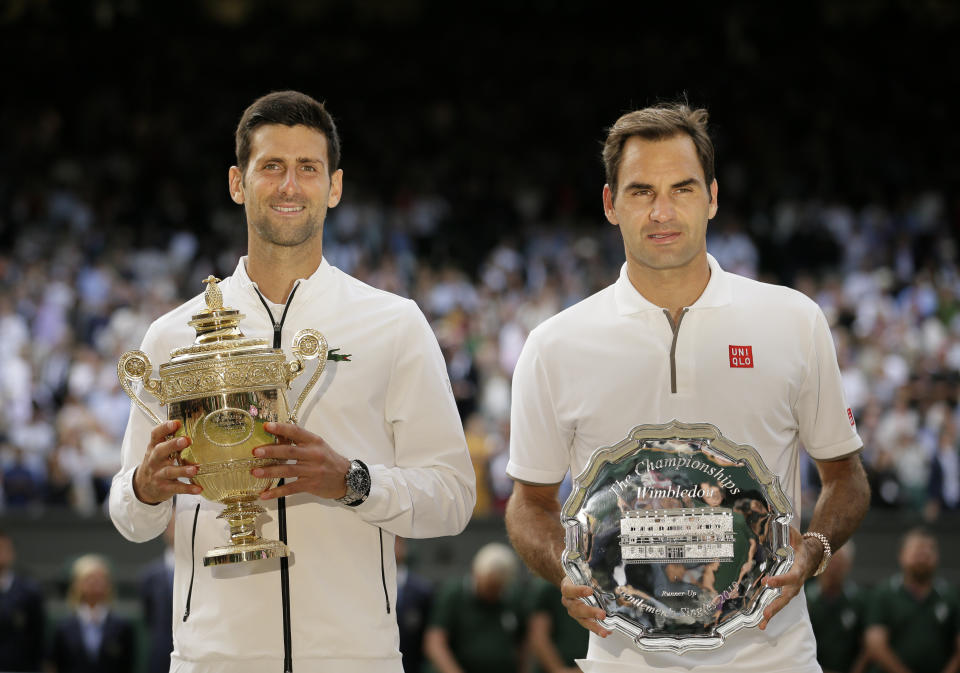 FILE - Serbia's Novak Djokovic, left, and Switzerland's Roger Federer pose with the trophies after the men's singles final match of the Wimbledon Tennis Championships in London, in this Sunday, July 14, 2019, file photo. There are plenty of intriguing story lines to follow on the grass courts. That includes Novak Djokovic's bid to equal Roger Federer and Rafael Nadal at 20 major titles and Serena Williams seeking her 24th. (AP Photo/Tim Ireland, File)