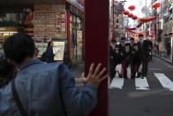 In this Feb. 13, 2020, photo, a group of students gather for a group picture in Yokohama's Chinatown, near Tokyo. A top Olympic official made clear Friday the 2020 Games in Tokyo will not be cancelled despite the virus that has spread from China. (AP Photo/Jae C. Hong)