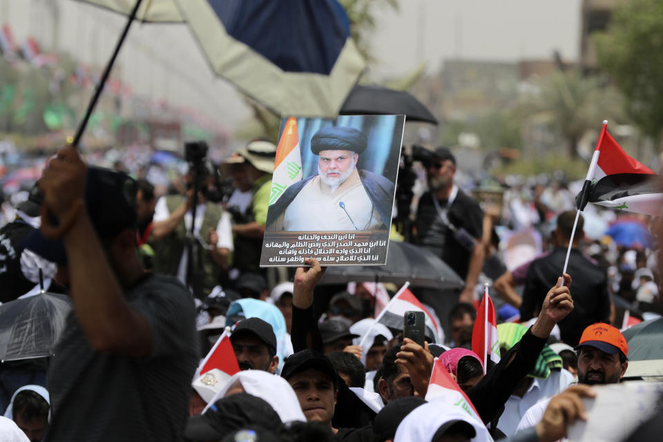 FILE - Followers of Shiite cleric Muqtada al-Sadr hold posters with his photo during an open-air Friday prayers in Sadr City, Baghdad, Iraq, July 15, 2022. Residents of the impoverished Baghdad suburb of Sadr City say they they support al-Sadr, an influential cleric who called on thousands of his followers to storm Iraq's parliament. Al-Sadr derives his political weight largely from their seemingly unending support. And yet, they are among Iraq’s most destitute. (AP Photo/Hadi Mizban, File)