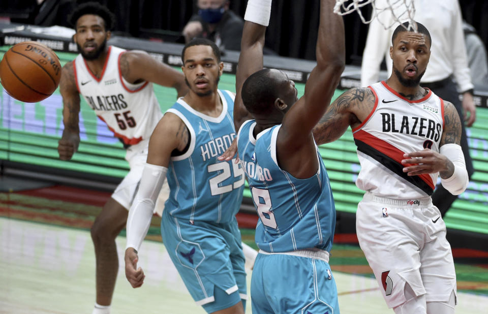Portland Trail Blazers guard Damian Lillard, right, passes the ball over Charlotte Hornets center Bismack Biyombo, second from right, as Hornets forward P.J. Washington looks on during the second half of an NBA basketball game in Portland, Ore., Monday, March 1, 2021. (AP Photo/Steve Dykes)